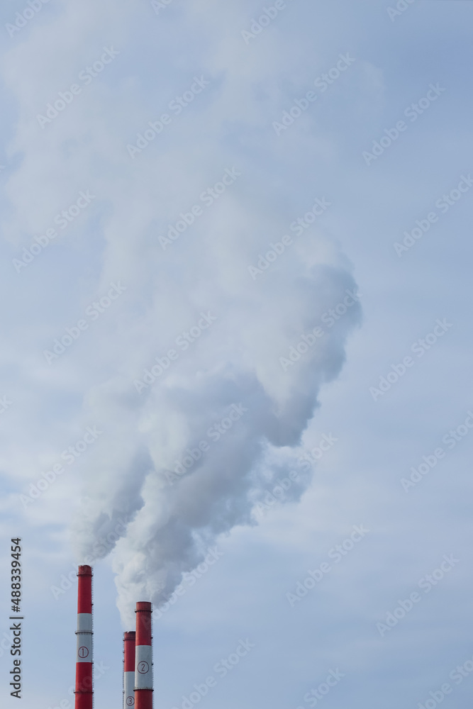 Three pipes of a thermal power plant close-up. Smoke rises from the chimneys into the sky. Place to copy. vertical.