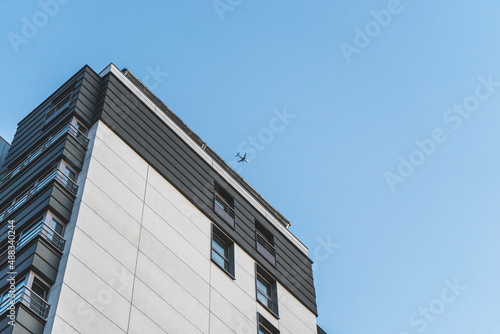 High building in Brussels, Belgium. Airplane is flying in the cloudless blue sky above