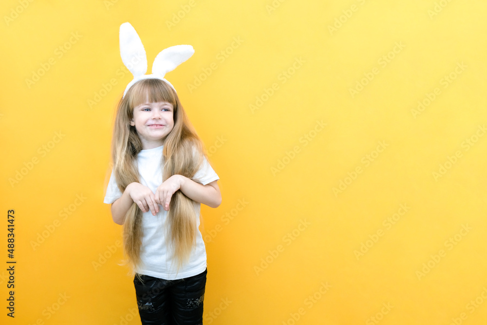 cheerful girl with rabbit ears on her head on a yellow background. Funny crazy happy child. Easter child. Preparation for the Easter holiday. promotional items. cheerful girl with rabbit ears on her head on a yellow background. Funny crazy happy child. Easter child. Preparation for the Easter holiday. promotional items.