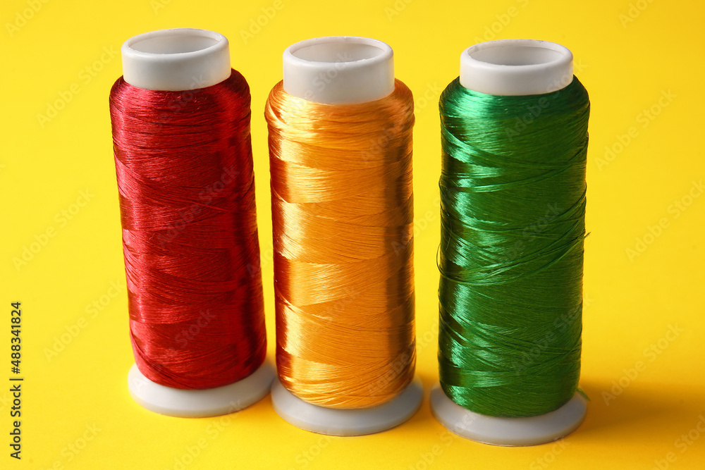 Thread spools on yellow background, closeup Thread spools on yellow background, closeup