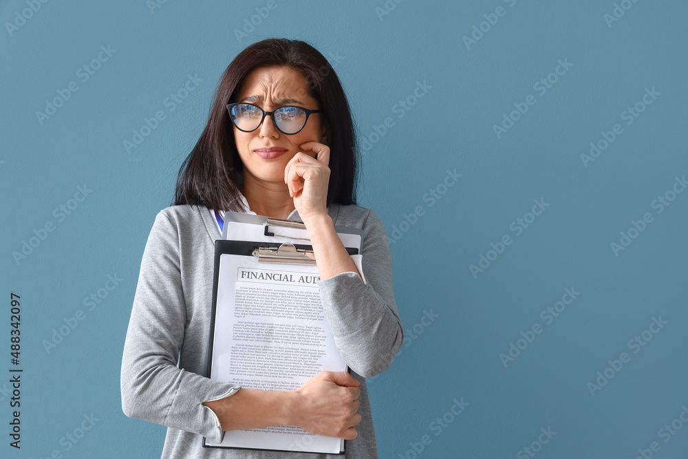 Worried female accountant on blue background Worried female accountant on blue background
