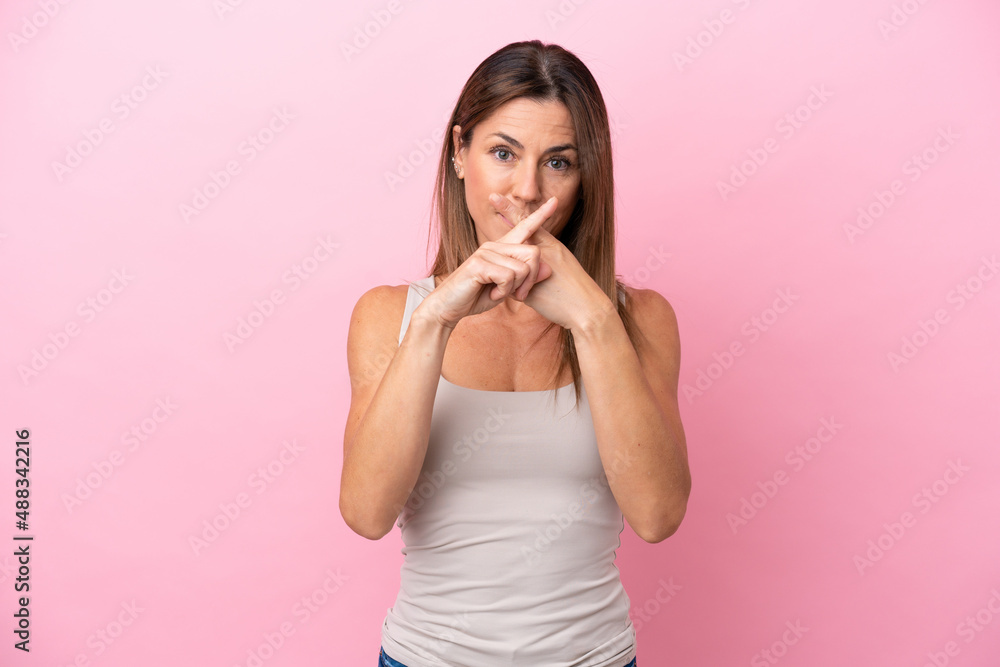 Middle age caucasian woman isolated on pink background showing a sign of silence gesture Middle age caucasian woman isolated on pink background showing a sign of silence gesture
