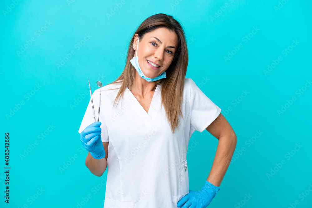Middle age doctor woman isolated on blue background posing with arms at hip and smiling Middle age doctor woman isolated on blue background posing with arms at hip and smiling