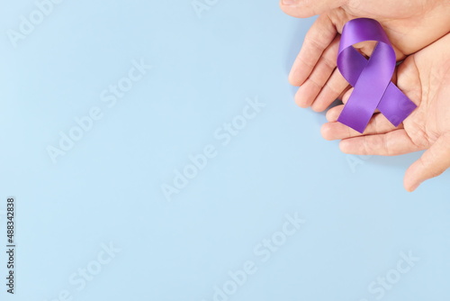 Top view of male hands holding purple ribbon color. Testicular, pancreatic cancer, epilepsy, leiomyosarcoma, lupus, Alzheimer's disease, Hodgkin lymphoma and cystic fibrosis awareness concept. photo