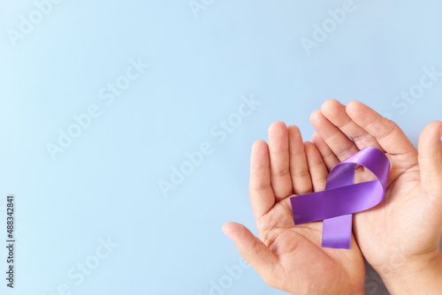 Top view of male hands holding purple ribbon color. Testicular, pancreatic cancer, epilepsy, leiomyosarcoma, lupus, Alzheimer's disease, Hodgkin lymphoma and cystic fibrosis awareness concept. photo