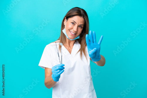 Middle age doctor woman isolated on blue background happy and counting four with fingers