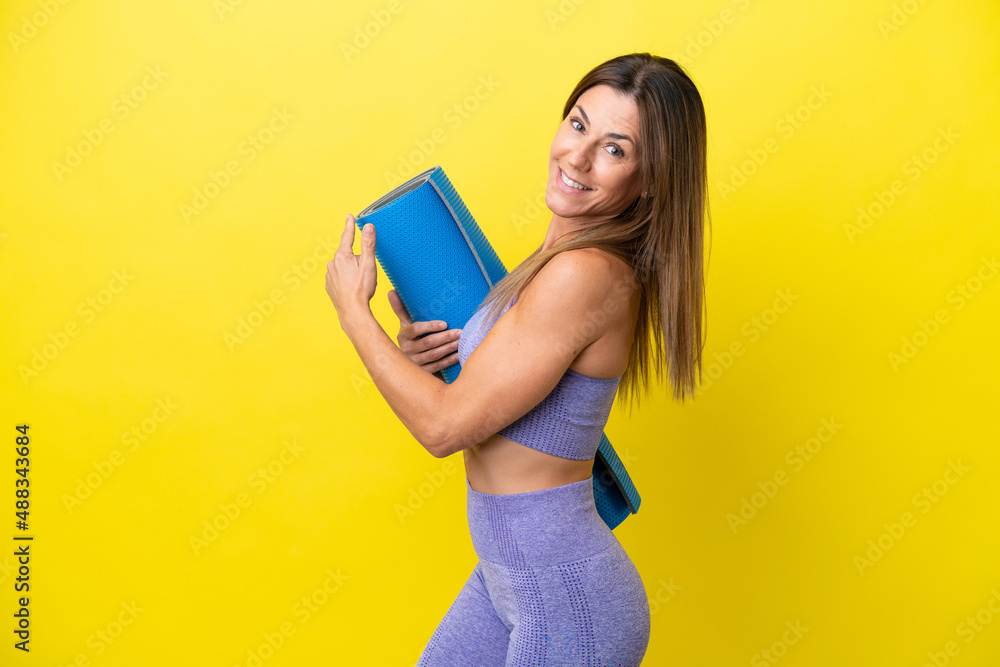 Sport woman going to yoga classes while holding a mat isolated non yellow background pointing back Sport woman going to yoga classes while holding a mat isolated non yellow background pointing back