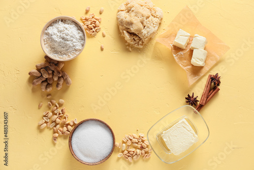 Fototapeta Naklejka Na Ścianę i Meble -  Frame made of fresh dough and ingredients for preparing peanut cookies on yellow background