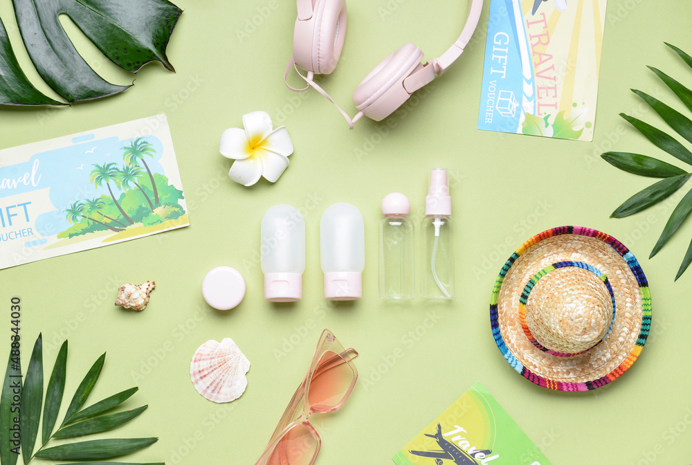 Composition with travel cosmetic bottles, beach accessories and palm leaves on green background Composition with travel cosmetic bottles, beach accessories and palm leaves on green background