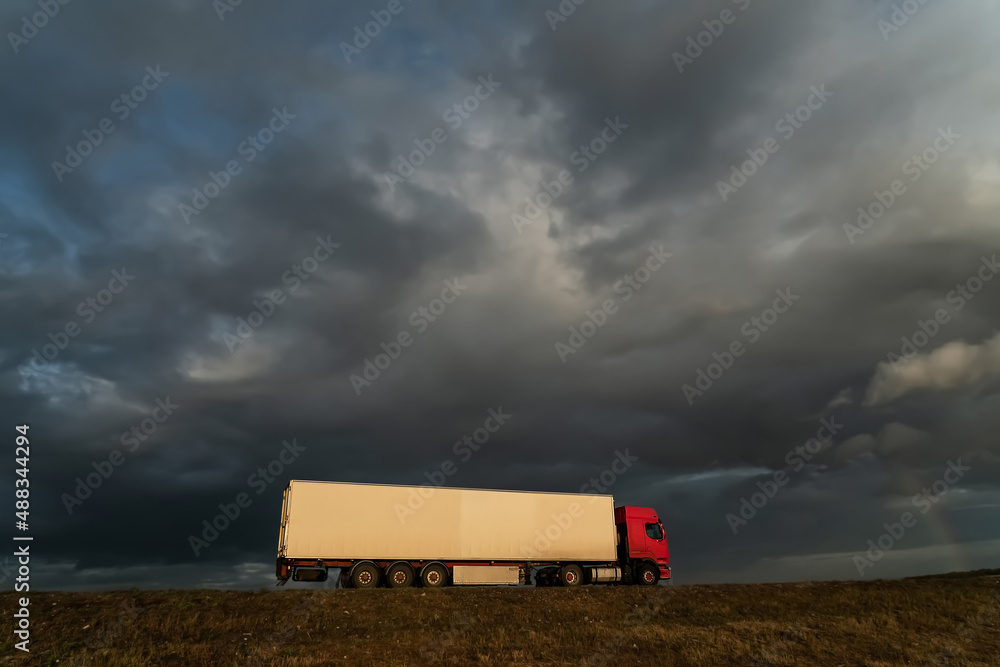 Freight truck under dramatic stormy sky with rainbow