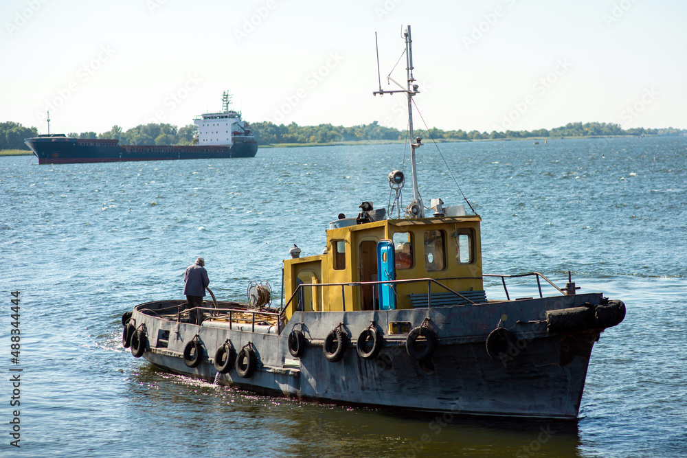 ship tugboat in the river on the background of a cargo ship ship tugboat in the river on the background of a cargo ship