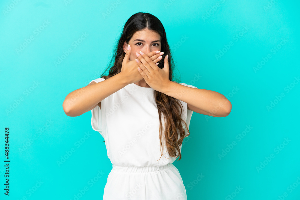 Young caucasian woman isolated on blue background covering mouth with hands Young caucasian woman isolated on blue background covering mouth with hands