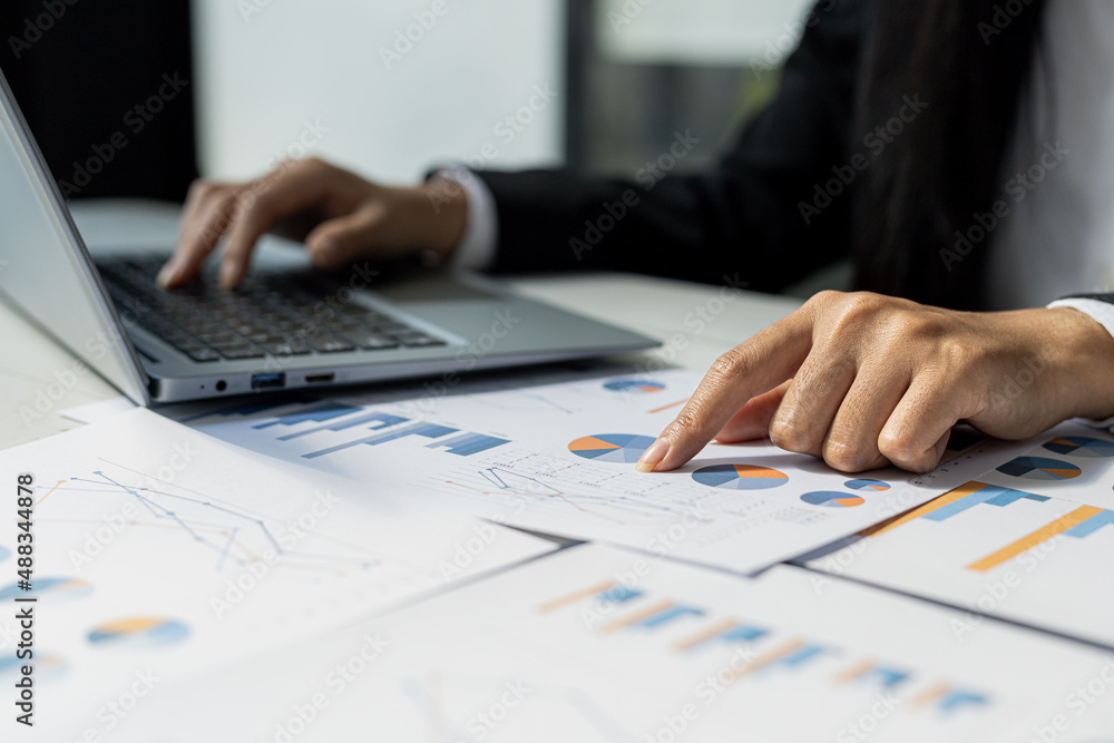 Businessman points to financial documents, he owns a startup company, he sits checking the company's financial summary prepared by the finance department. Management concept of startup company. Businessman points to financial documents, he owns a startup company, he sits checking the company's financial summary prepared by the finance department. Management concept of startup company.