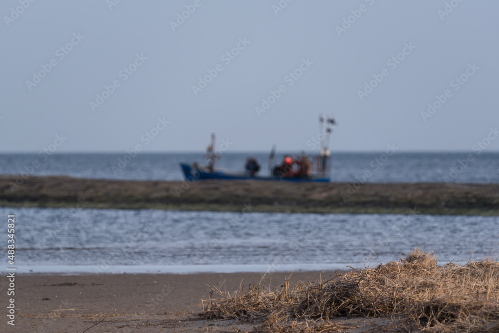 SEA COAST - The seashore with a fishing boat in the background 
