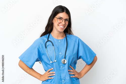 Young surgeon doctor caucasian woman isolated on white background posing with arms at hip and smiling