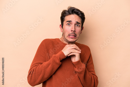 Young caucasian man isolated on beige background scared and afraid.