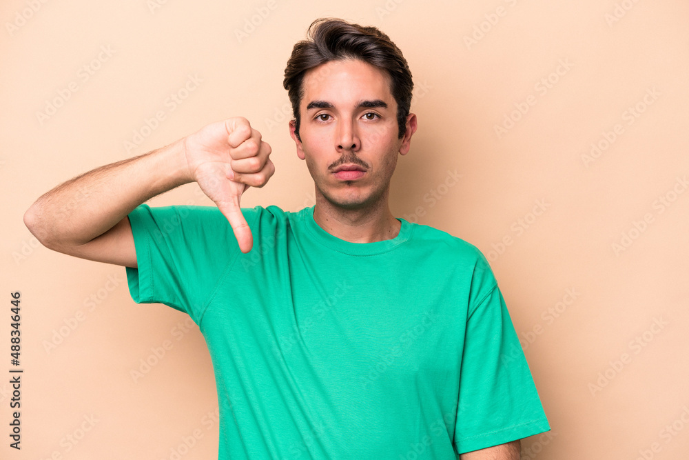 Young caucasian man isolated on beige background showing a dislike gesture, thumbs down. Disagreement concept. Young caucasian man isolated on beige background showing a dislike gesture, thumbs down. Disagreement concept.
