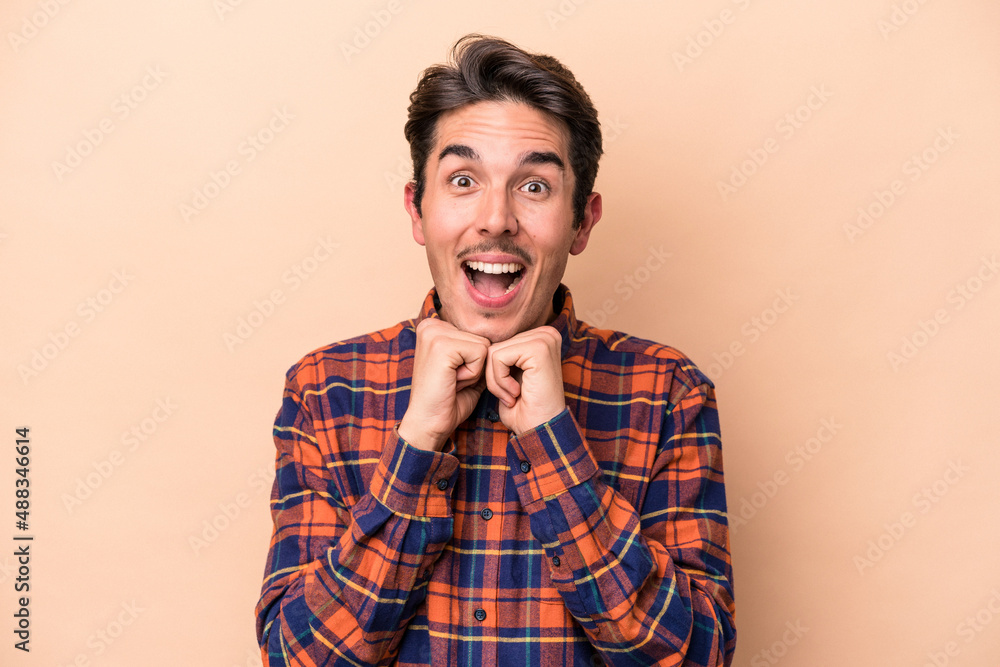 Young caucasian man isolated on beige background praying for luck, amazed and opening mouth looking to front. Young caucasian man isolated on beige background praying for luck, amazed and opening mouth looking to front.