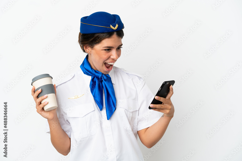 Airplane stewardess caucasian woman isolated on white background holding coffee to take away and a mobile Airplane stewardess caucasian woman isolated on white background holding coffee to take away and a mobile