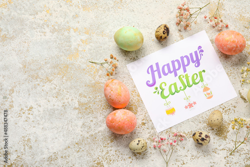 Beautiful Easter composition with greeting card, painted eggs and flowers on light background