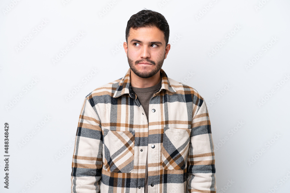 Young Brazilian man isolated on white background having doubts while looking up Young Brazilian man isolated on white background having doubts while looking up