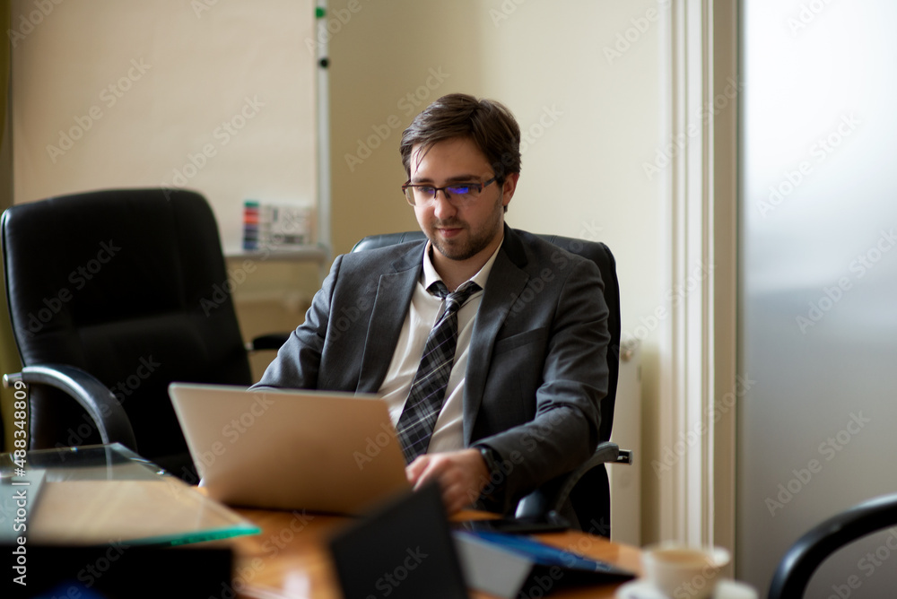 Young serious professional business man, focused male student wearing glasses working on laptop Young serious professional business man, focused male student wearing glasses working on laptop