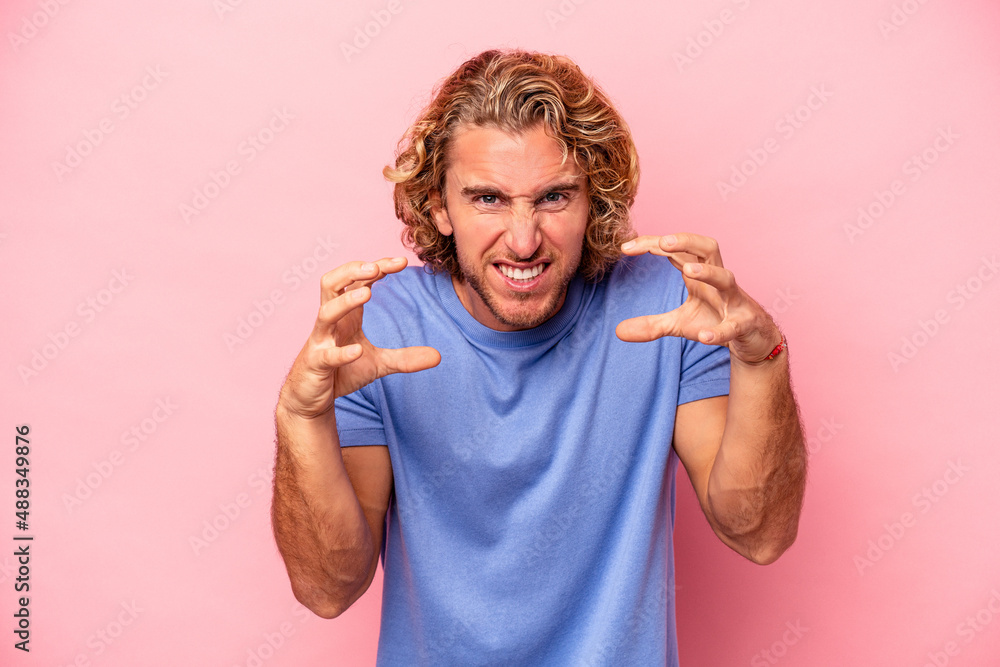 Young caucasian man isolated on pink background upset screaming with tense hands. Young caucasian man isolated on pink background upset screaming with tense hands.