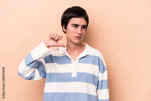 Young caucasian woman isolated on beige background showing a dislike gesture, thumbs down. Disagreement concept.