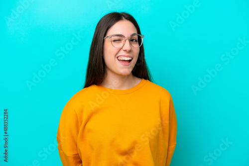 Young girl isolated on blue background With glasses and happy expression © luismolinero