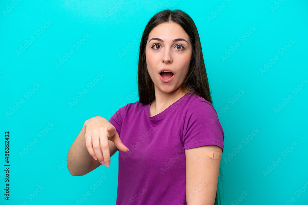 Young girl with band-aids isolated on blue background surprised and pointing front Young girl with band-aids isolated on blue background surprised and pointing front
