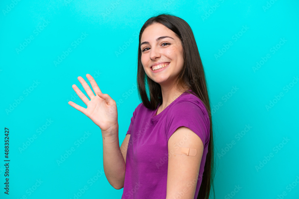 Young girl with band-aids isolated on blue background saluting with hand with happy expression Young girl with band-aids isolated on blue background saluting with hand with happy expression