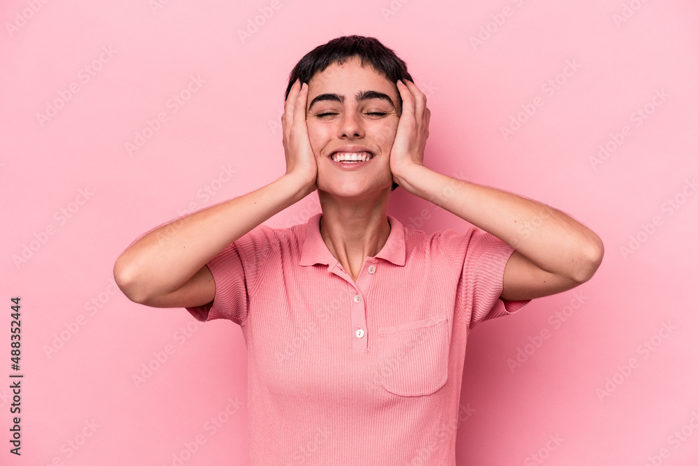Young caucasian woman isolated on pink background laughs joyfully keeping hands on head. Happiness concept. Young caucasian woman isolated on pink background laughs joyfully keeping hands on head. Happiness concept.