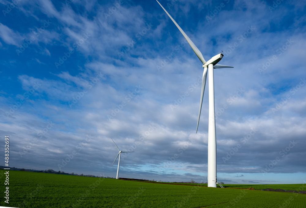 Two wind turbines generating renewable energy on a clear windy day