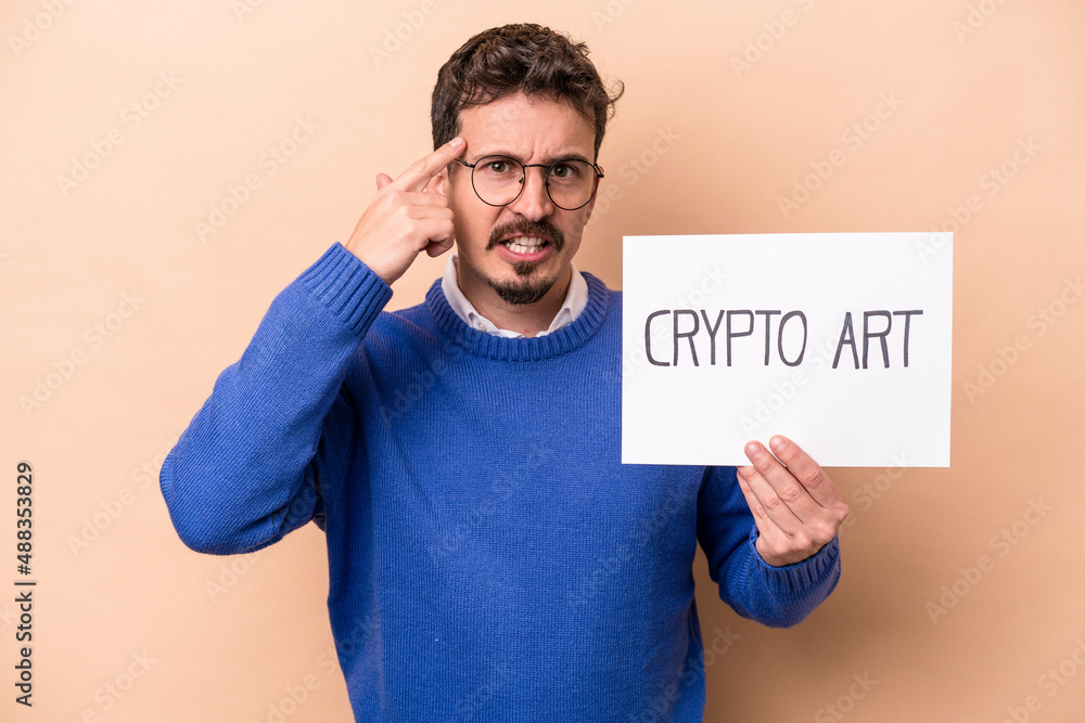Young caucasian man holding a crypto art placard isolated on beige background showing a disappointment gesture with forefinger. Young caucasian man holding a crypto art placard isolated on beige background showing a disappointment gesture with forefinger.