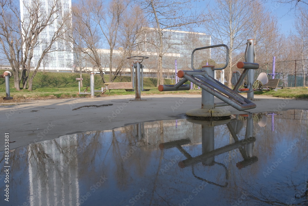 Reflection of tall building at puddle of water by photo of public children park. Reflection of tall building at puddle of water by photo of public children park.