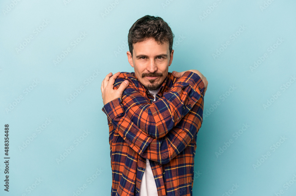 Young caucasian man isolated on blue background hugs, smiling carefree and happy. Young caucasian man isolated on blue background hugs, smiling carefree and happy.