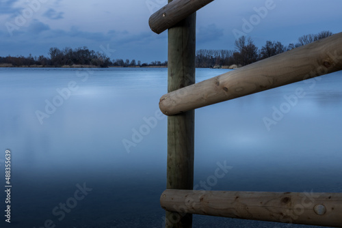 Wooden fence on the shore of a lake in the blue hour photo
