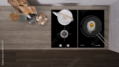Dark wooden kitchen close up, induction and gas hob with pot and fried egg in a pan. Vase with spikes, cutting boards. Top view, plan, above with copy space, interior design photo