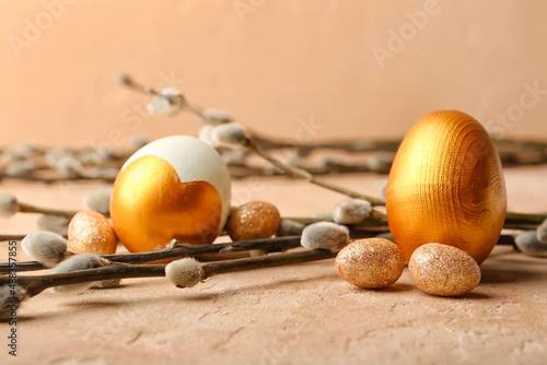 Painted Easter eggs and pussy willow branches on color background
