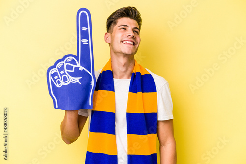 Photos Young sports fan man isolated on yellow background dreaming of achieving goals a