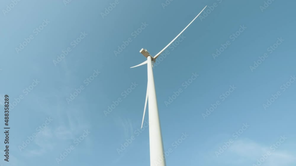 Close up of huge wind propeller working constantly on eco farm over blue sky. Concept of electric power production and clean energy. Close up of wind propeller working on field over blue sky. Close up of huge wind propeller working constantly on eco farm over blue sky. Concept of electric power production and clean energy. Close up of wind propeller working on field over blue sky.