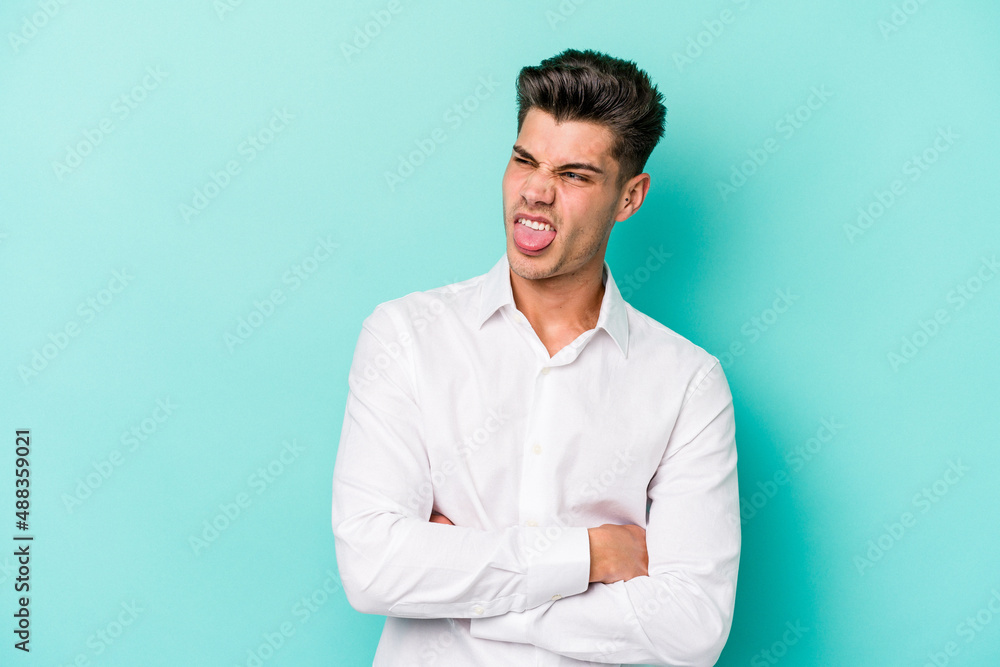 Young caucasian man isolated on blue background funny and friendly sticking out tongue. Young caucasian man isolated on blue background funny and friendly sticking out tongue.