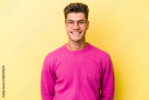 Young caucasian man isolated on yellow background happy, smiling and cheerful.