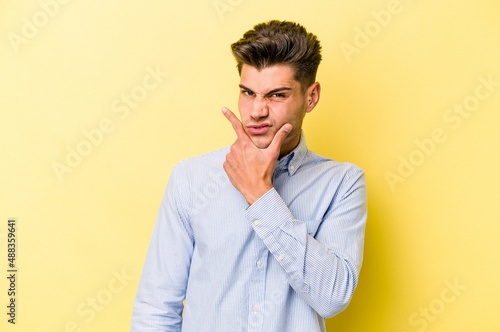Young caucasian man isolated on yellow background contemplating, planning a strategy, thinking about the way of a business. © Asier
