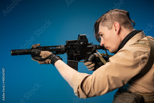 a male special agent soldier in a bulletproof vest with an automatic rifle on a blue background