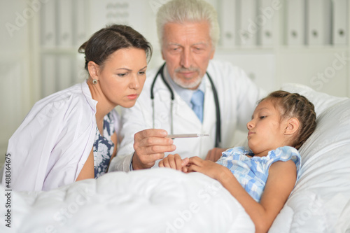 Senior doctor visiting little girl in hospital
