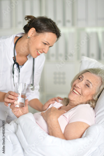 Sick senior woman portrait in hospital with doctor