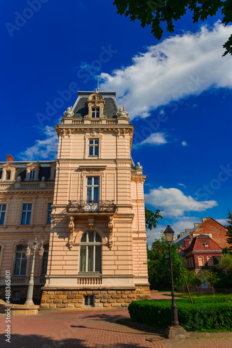 Eastern Europe historical district of Ukrainian city medieval palace building campus tower exterior architecture side in vibrant spring season time with colorful green plants and blue sky