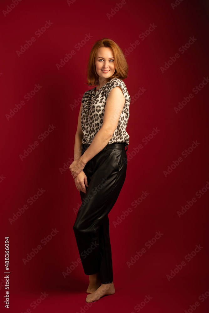 a modern stylish girl with golden hair in leather trousers and a spotted blouse on a red background a modern stylish girl with golden hair in leather trousers and a spotted blouse on a red background