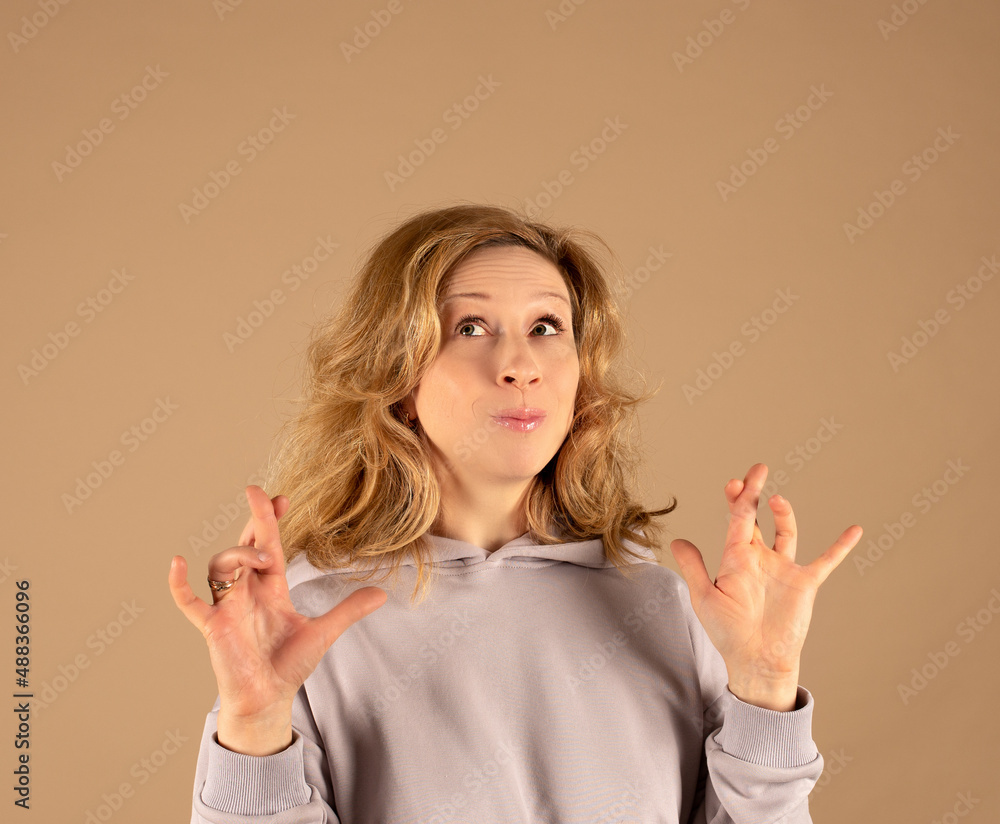 Studio portrait of a funny red-haired curly-haired woman. She has her fingers crossed and is looking up Studio portrait of a funny red-haired curly-haired woman. She has her fingers crossed and is looking up